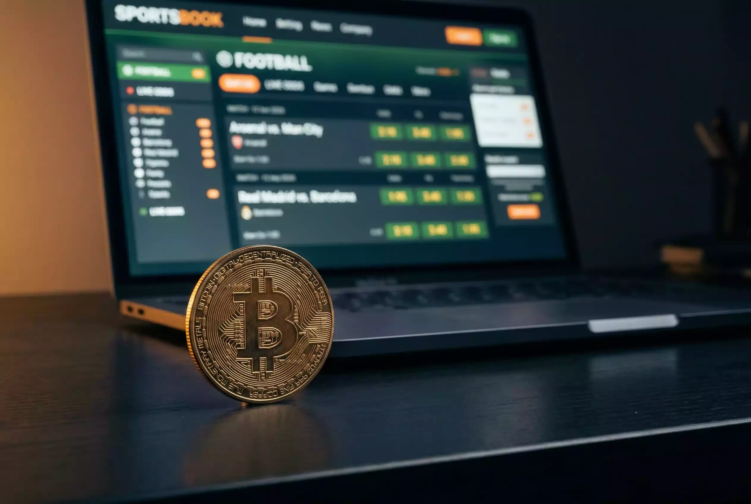 Bitcoin-mynt pa en laptop med sportbettingsida i bakgrunden